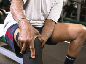 Man holding his knee in gym