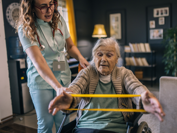 Older woman stretches arms with exercise band.