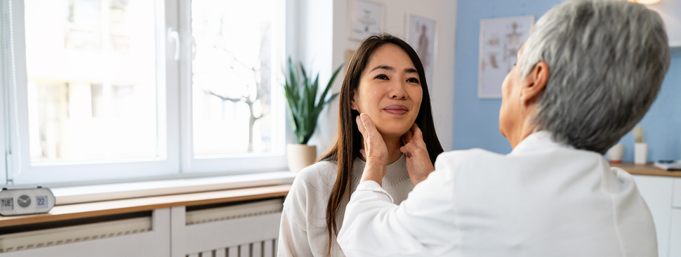 A young woman has her neck and thyroid examined