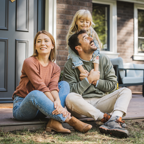 Young family with little girl having fun in front of there house.