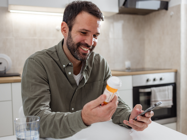 Man with medication bottle and a smartphone