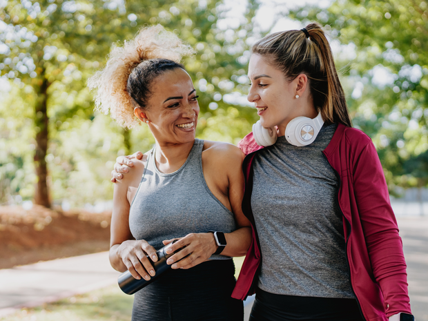 Two women embrace after excising outdoors.