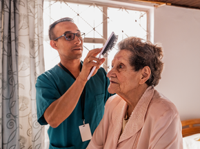 In-home aide brushes an elderly woman's hair.
