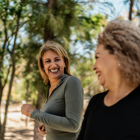 two mature women walking and talking in a park