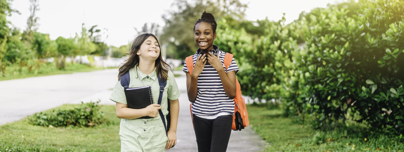 Tween girls talking and laughing while walking to school.