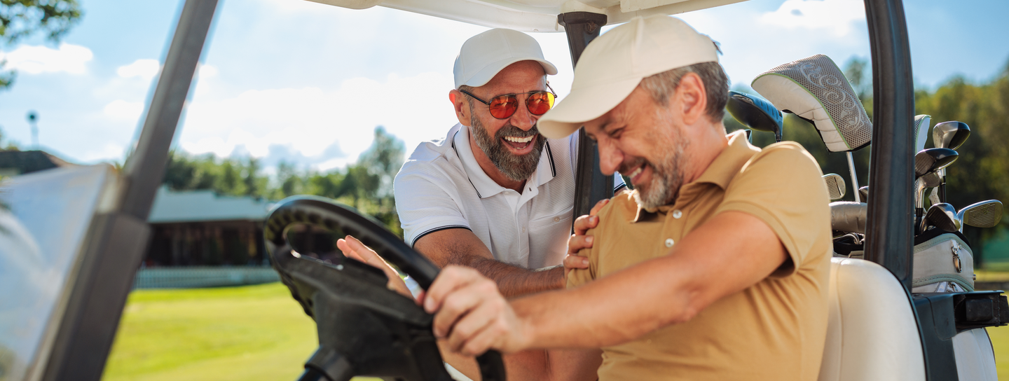 Two men sitting in golf cart laughing