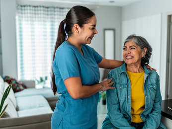 Healthcare professional smiles with an in-home patient.