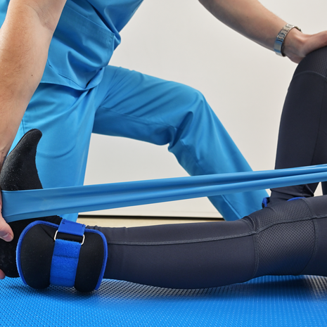 Female lying down receiving physical therapy to recovering leg injury