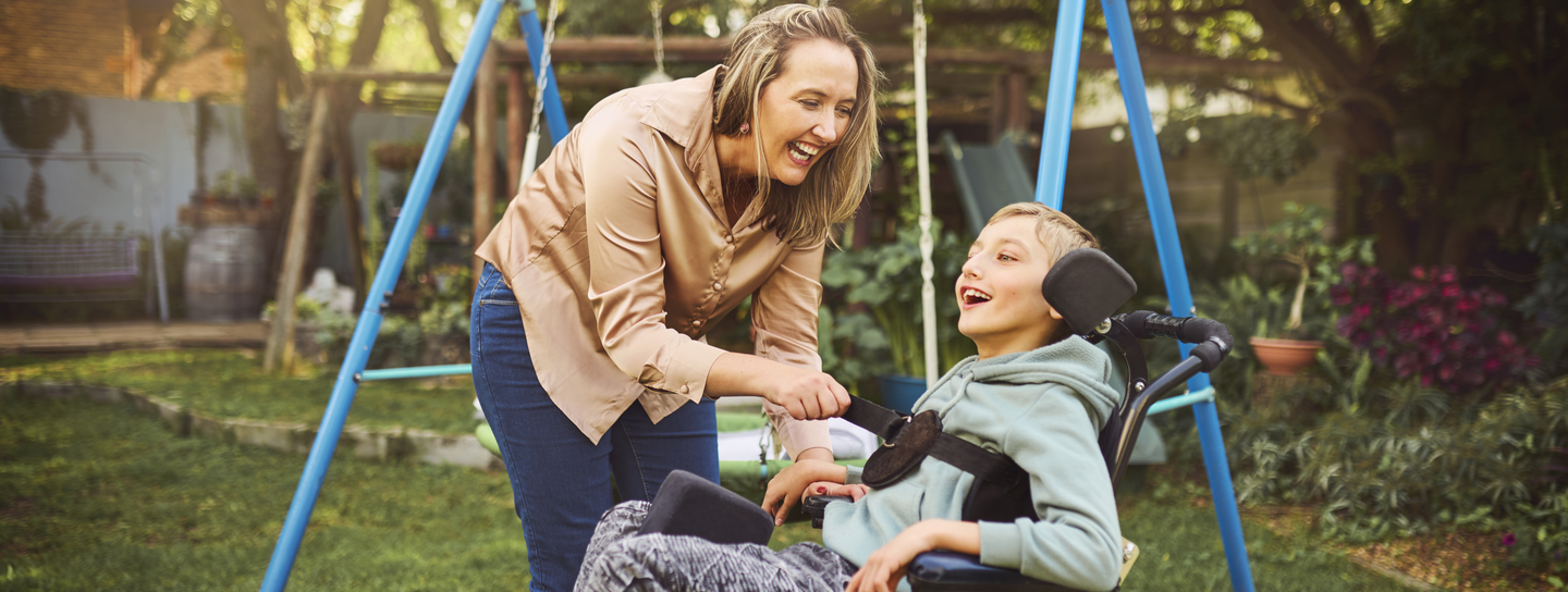 Mother with son in wheelchair having fun outside