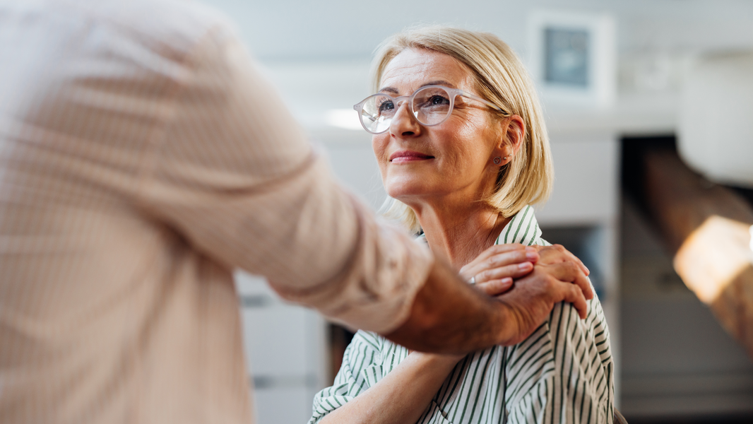 Senior woman is comforted by man putting a hand on her shoulder