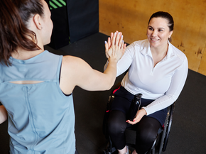 Patient in wheelchair high fiving her therapist