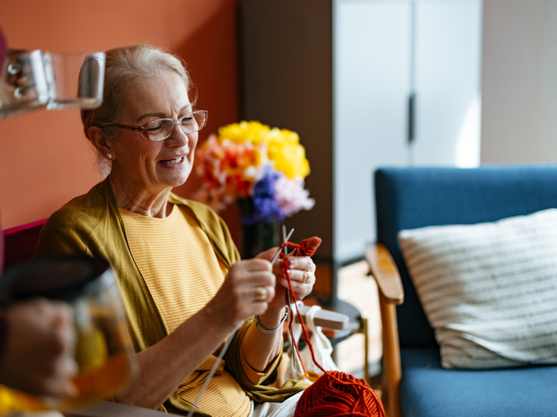 Older woman smiles while putting colorful bouquet of flowers together.
