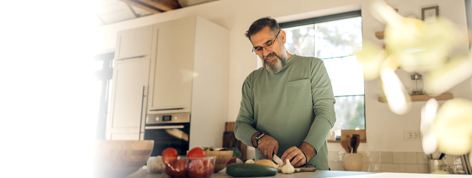 A man looks out of the window, holding a cup of coffee