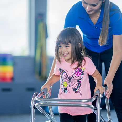 Girl works on walking with the help of her walker and her physical therapist