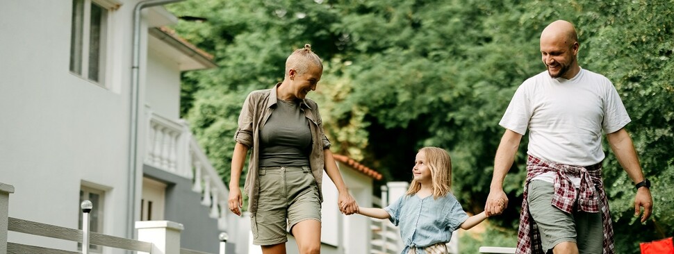 Father and mother are holding the hands of a happy little girl