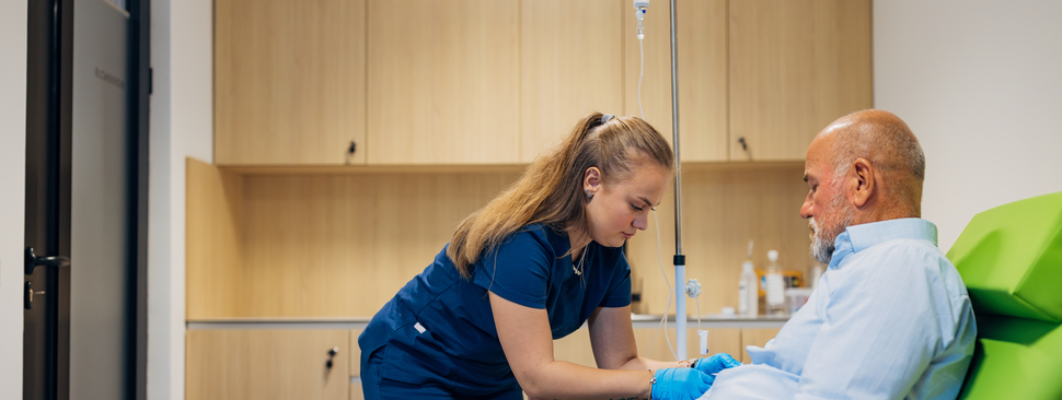A nurse takes a blood sample from a mature man.
