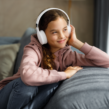 Smiling little girl listening music at home