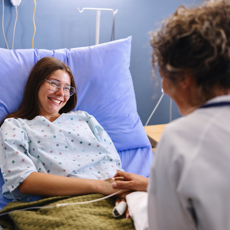 Doctor smiling at young female patient in hospital