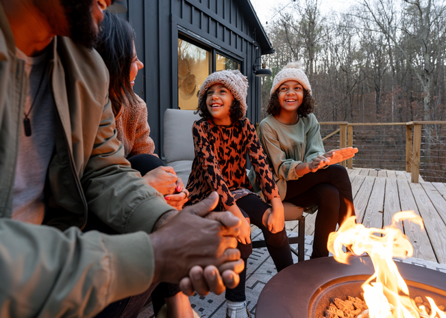 A family sits on the patio, roasting marshmallows together