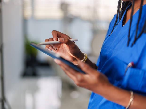 Close up to healthcare worker with blue scrubs hands using digital tablet