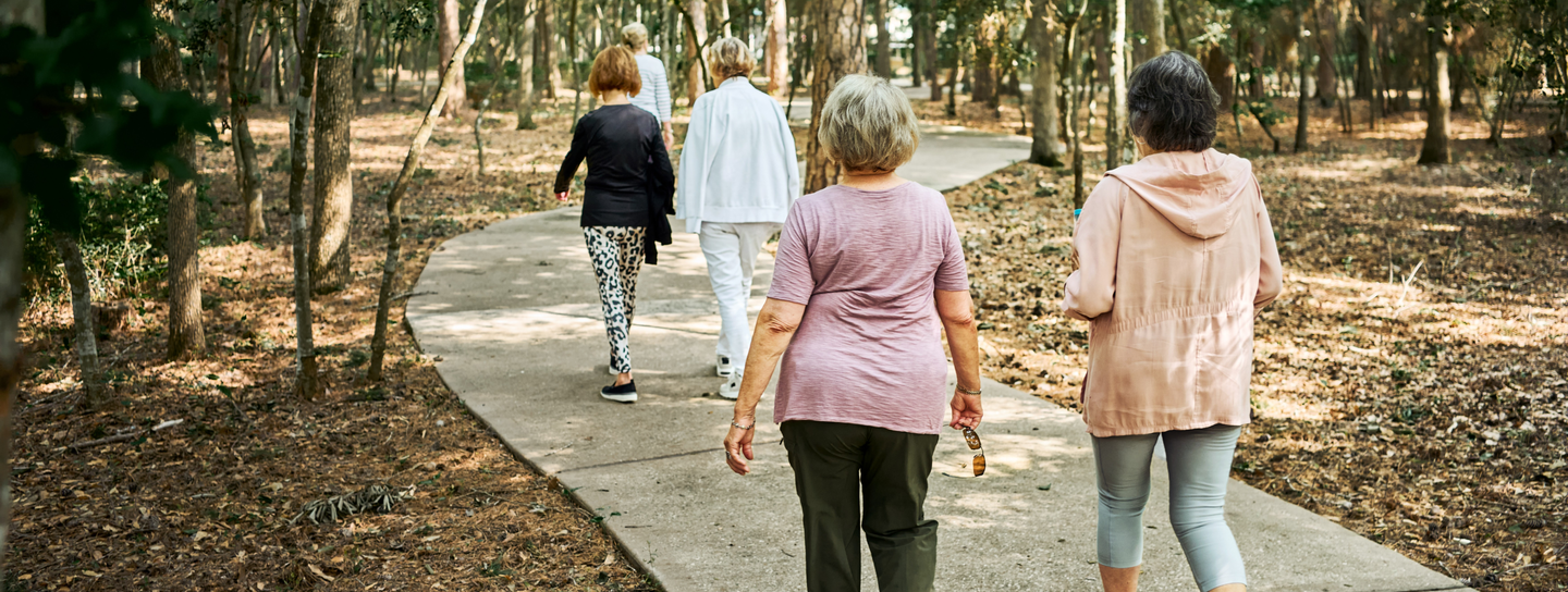 Senior women walking together on park trail