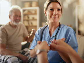 Nurse at home holds hand with hospice patient.