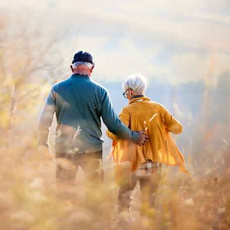 Elderly patient smiles while holding hands with at-home provider.