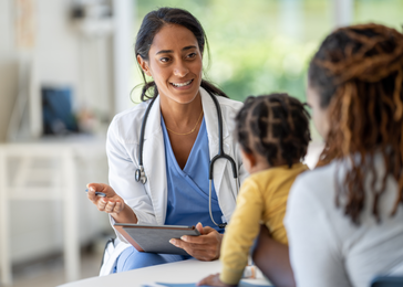 A doctor speaks with a mother who has her son on her lap