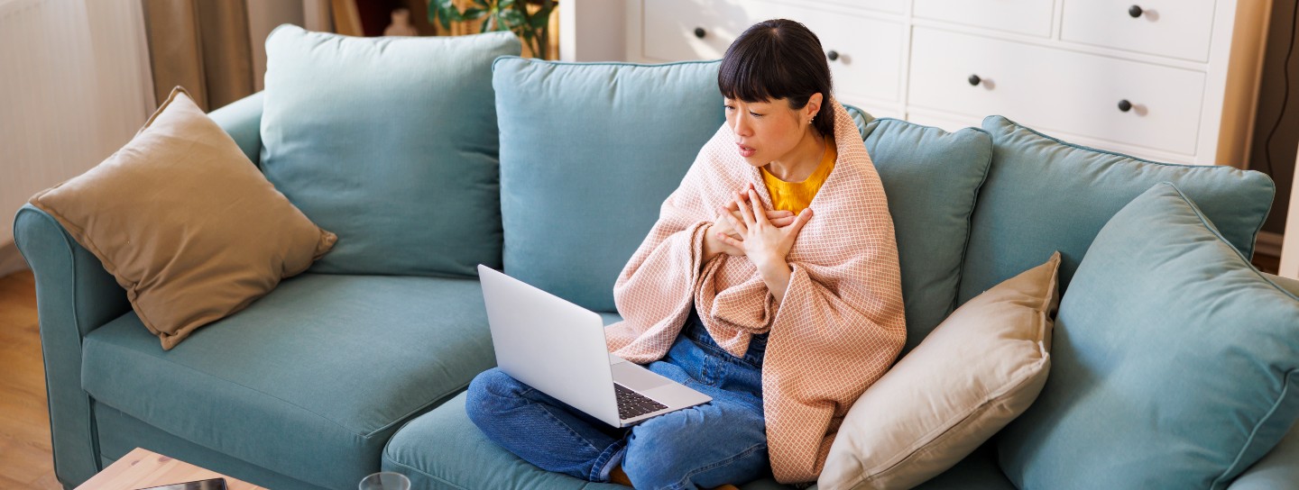Woman having online doctor's exam using laptop computer while sick at home
