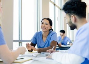 Young students nurses having conversation while sitting at a desk