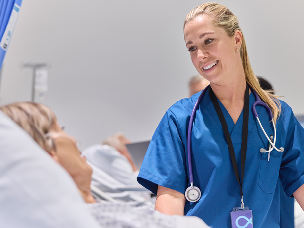 Provider smiles while tending to patient on bed.