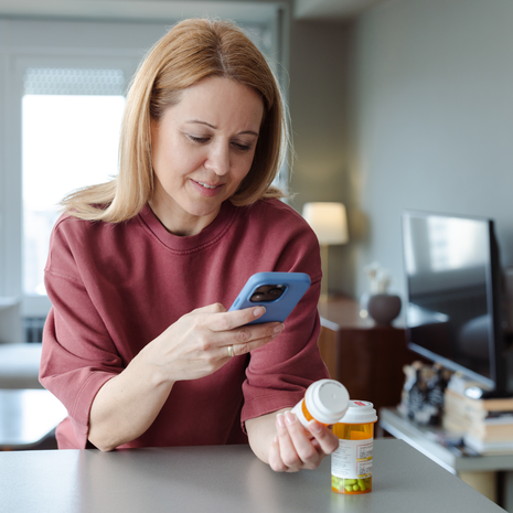 Man with glasses smiles while walking through downtown area.
