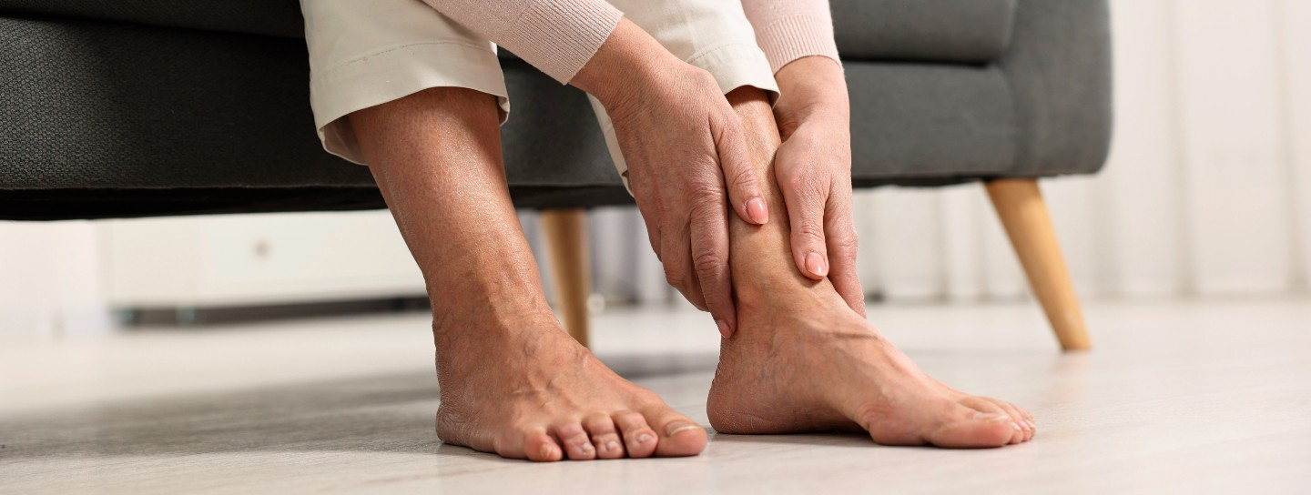 A person leans down, holding their ankle
