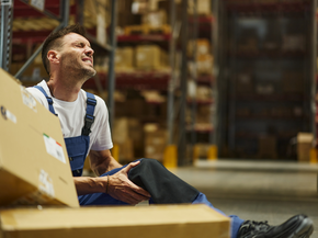 Man worker holding his leg in pain after injury at workforce.