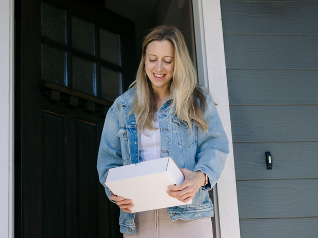 Woman picking up package delivery at front door of home