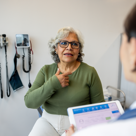 A woman describes symptoms to her doctor who is listening to her.