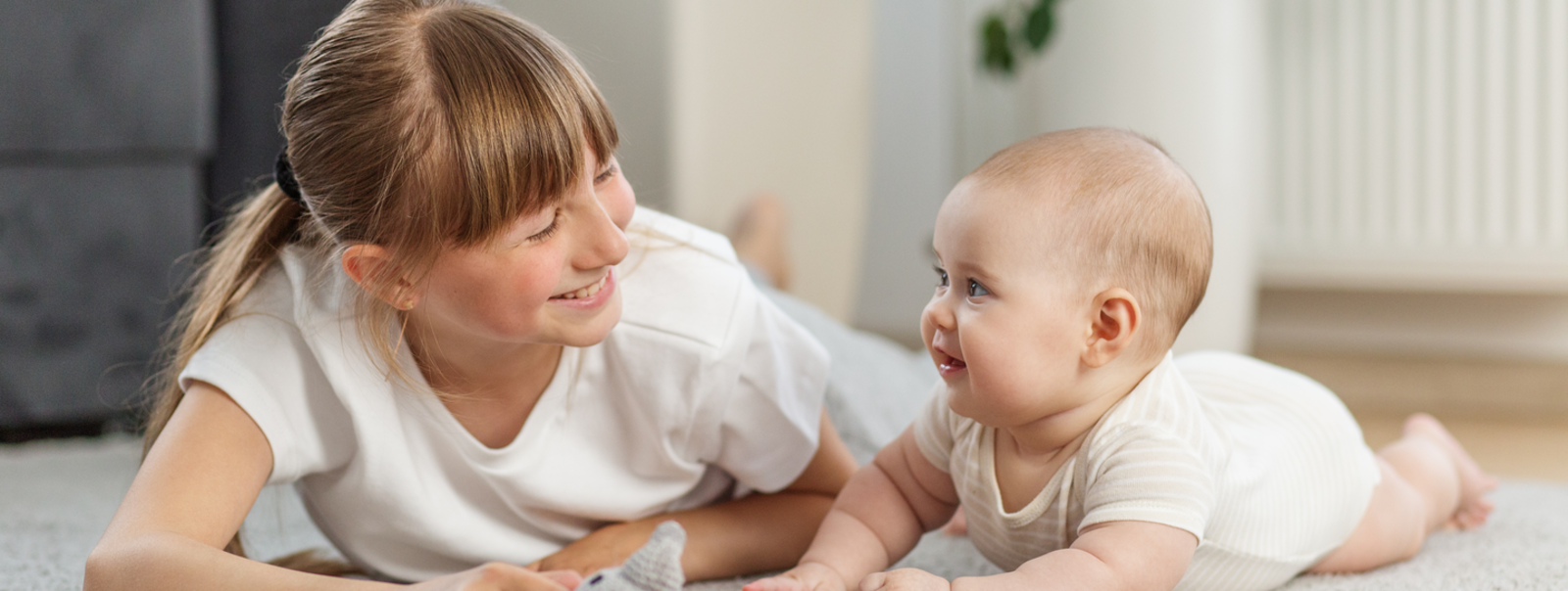 Teen babysitter reading a book to a younger child.