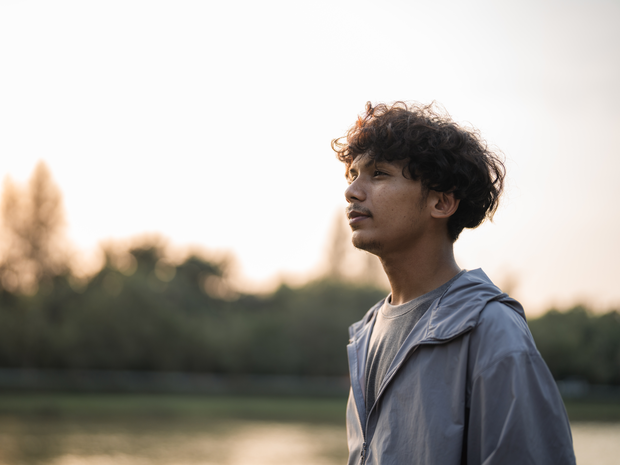 Teenage boy looks out at sky.