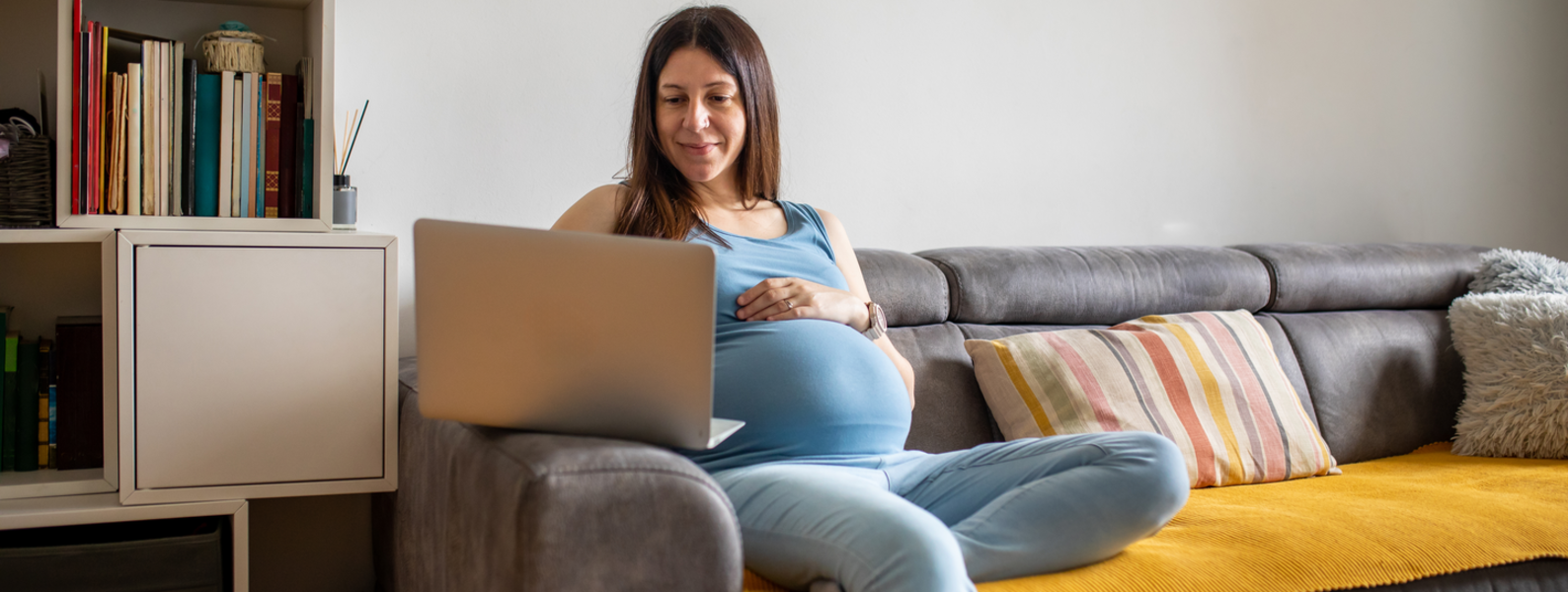 Pregnant woman using a laptop at home. 
