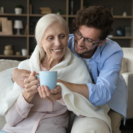Caring grownup grandson cover shoulders of grandma
