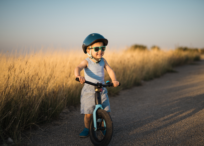 Young boy riding a bike wearing a helmet.