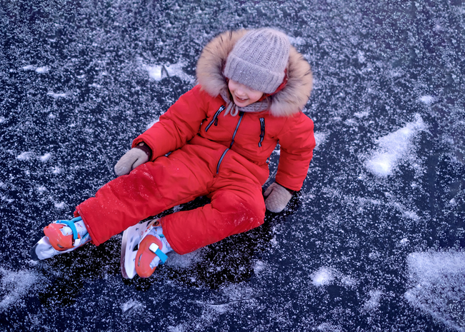 Child laying on ice after falling while ice skating.