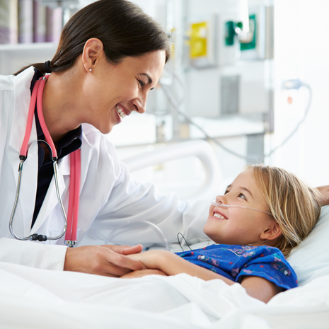 Doctor smiling at young female patient in hospital