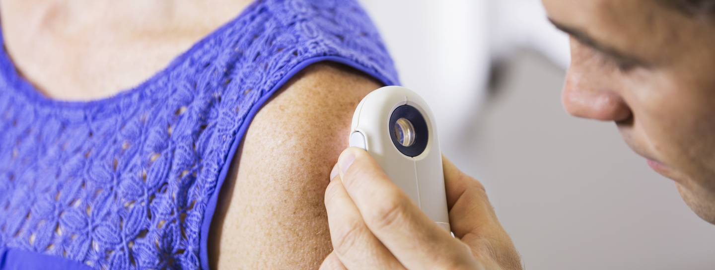 A doctor looks at the skin on a patient's arm