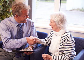An older woman shakes hands with a doctor