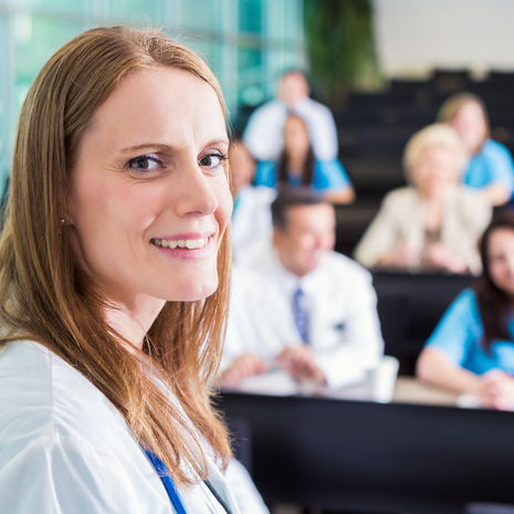 Doctor smiling in a room with other doctors.