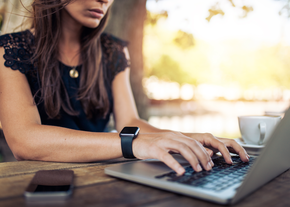 A woman works at a computer while wearing a smart watch
