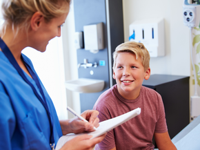 A boy looking at a nurse writing something down