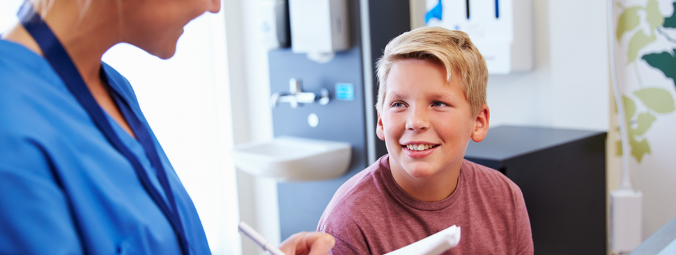 A boy looking at a nurse writing something down
