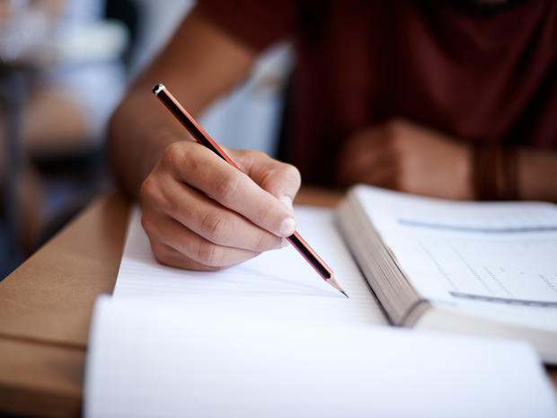 Man writing in book with pencil.